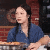 a woman with pigtails is sitting at a table with a plate of food and a glass of soda .