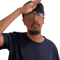 a man wearing glasses and a blue shirt salutes