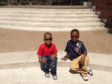 two young boys wearing sunglasses sit on steps