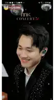 a man in a black jacket is smiling in front of a screen that says mk concert
