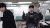 a man wearing a black shirt that says " irtee " stands in a room