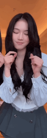 a woman with long black hair is wearing a striped shirt and a black skirt