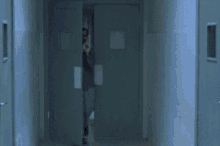 a man in a blue shirt is running in a hallway