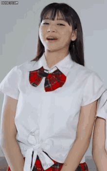 a girl in a white shirt with a red plaid tie