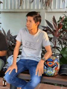 a man is sitting on a bench wearing a balenciaga shirt