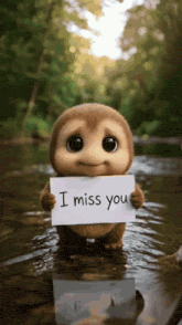 a small stuffed animal is holding a sign that says i miss you