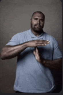a man wearing a blue shirt is making a hand gesture