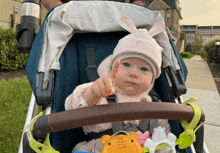 a baby in a stroller wearing a pink bunny hat