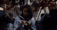 a girl in a school uniform is sitting in a chair holding a pen and a piece of paper .