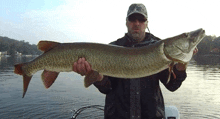 a man holding a large fish in his hands with a hat that says ' tnt ' on it