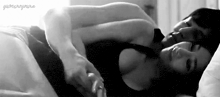 a black and white photo of a man and a woman sleeping in bed .