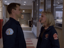 a man and a woman are standing in a hallway and the woman is wearing a chicago fire department uniform