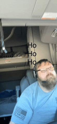 a man with a beard wearing headphones and a blue shirt with an american flag on his arm says ho ho ho