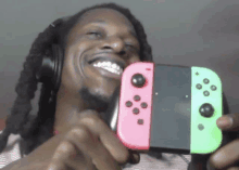 a man wearing headphones is holding a pink and green nintendo switch controller