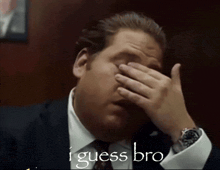 a man in a suit and tie is covering his face with his hand and the words " i guess bro " written below him