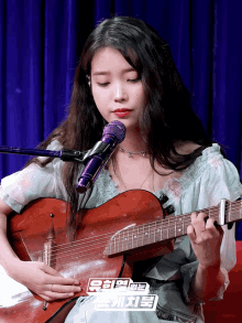 a woman singing into a microphone while holding a guitar with a sticker that says ' iu ' on it