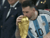 a soccer player with the number 10 on his jersey is kissing a trophy