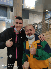 two men are posing for a picture and one has a jacket that says tribe on it