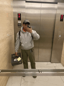 a man taking a picture of himself in an elevator while holding a box that says ' ice cream ' on it