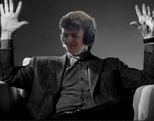 a man wearing headphones is sitting in a chair with his arms in the air