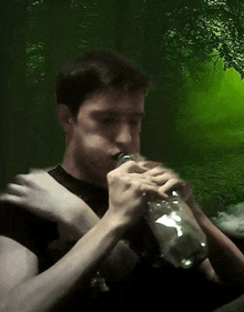 a man is drinking from a plastic bottle in front of a green background