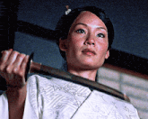 a woman in a white kimono is holding a sword in her hands