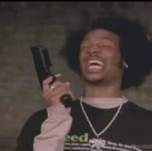 a man is holding a gun and smiling while wearing a shirt that says seed