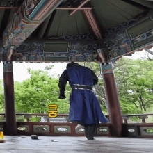 a man in a blue coat is standing under a gazebo with a yellow sign that says ' mr ' on it