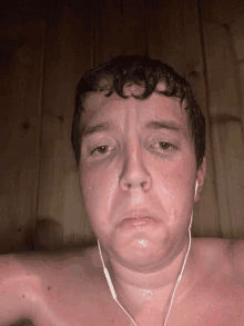 a shirtless man wearing ear buds looks tired and sweaty