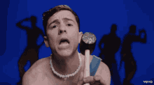 a man with a pearl necklace is holding a dumbbell in front of a blue background with the word vevo on it