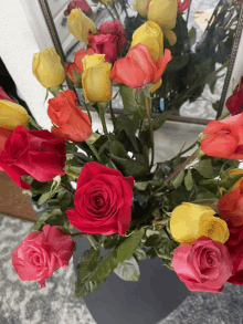 a bunch of red and yellow roses sitting in front of a mirror