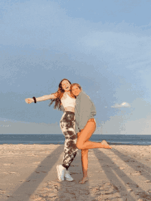 two girls posing for a picture on a beach with one wearing a sweatshirt that says calvin klein