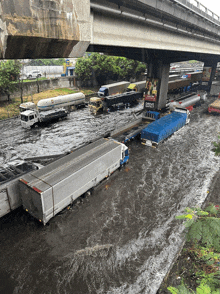 several trucks are driving through a flooded area and one of them has a sign on the back that says ' trucks '