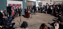 a man stands at a podium with a sign that says ' trump ' on it