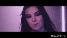 a close up of a woman 's face in a dark room with purple lights .