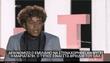 a man with curly hair is on a tv screen with a caption in greek