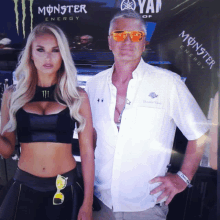 a man and a woman are posing for a picture in front of a monster energy sign