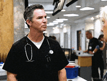 a man with a stethoscope around his neck is standing in a hospital hallway