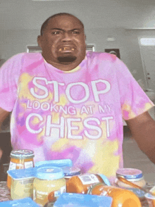 a man wearing a tie dye shirt that says stop looking at my chest