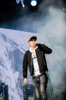 a man singing into a microphone while wearing a black jacket and a white shirt