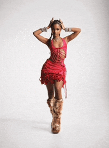 a woman in a red dress and furry boots is standing with her hands on her head