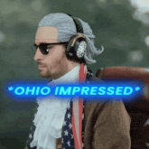 a man wearing a wig and headphones is sitting in front of a sign that says " ohio impressed "