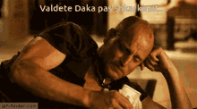 a bald man laying down with the words valdete daka pas shkarkimit