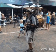 a man playing a guitar and a drum on a brick sidewalk with the words viralhog written on the bottom