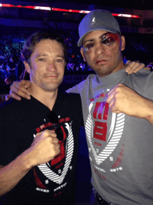 a man wearing a shirt that says mixed martial arts poses with another man