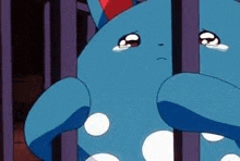 a blue pokemon is crying behind bars .