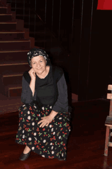 a woman in a floral skirt sits on the floor