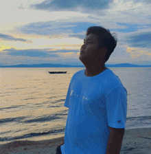 a man wearing a blue champion shirt stands on the beach