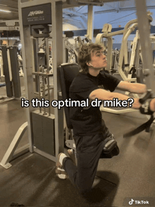 a man is kneeling down in front of a machine that says life fitness on it