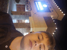 a young man stands in front of a building that has a sign that says ' open ' on it